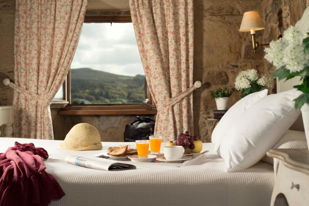 a bed with a breakfast on it with a window at A Casa da Torre Branca in Santiago de Compostela