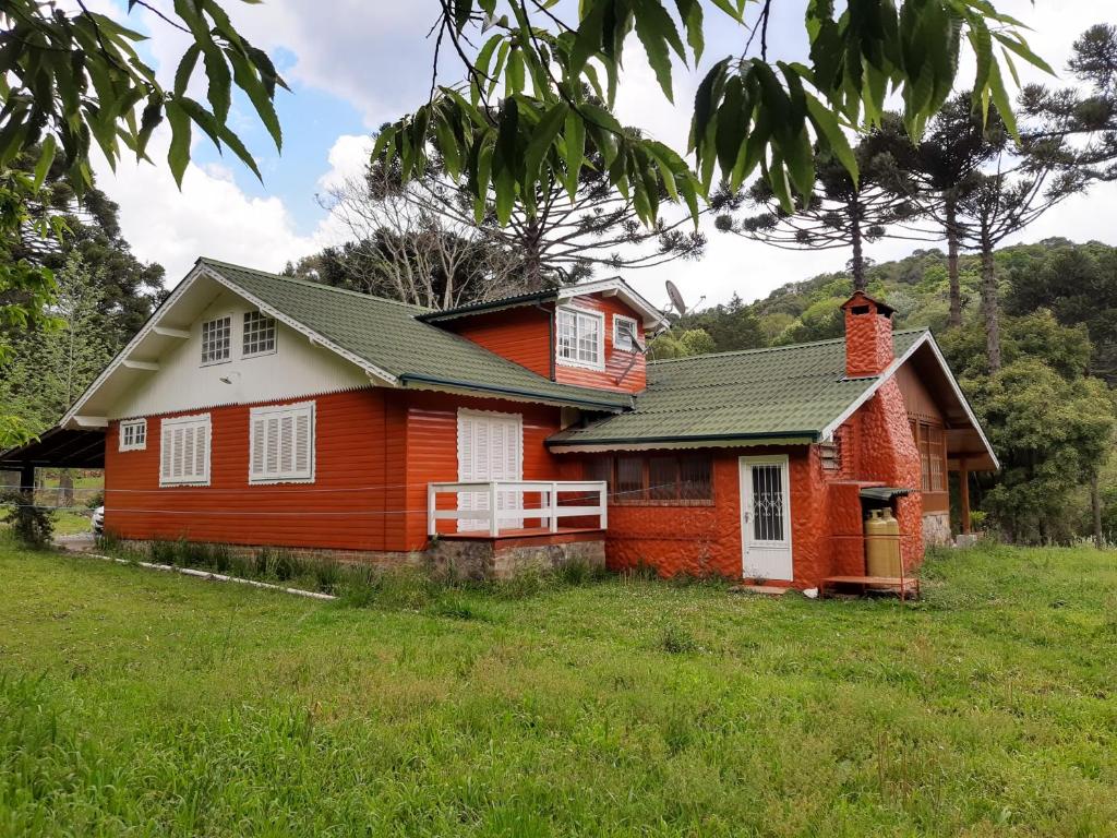 uma casa vermelha e branca num campo em CASARÃO DA CASCATA em Gramado