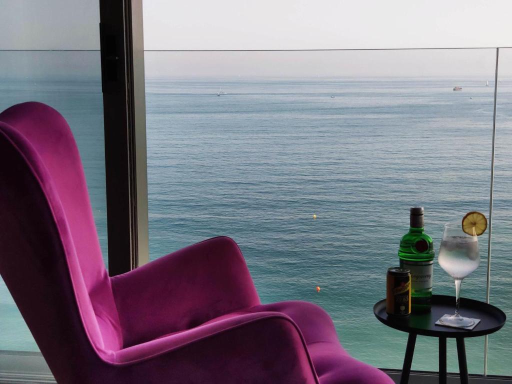una sedia viola e un tavolo con una bottiglia di vino di Exclusive Malaga Skyline a Málaga