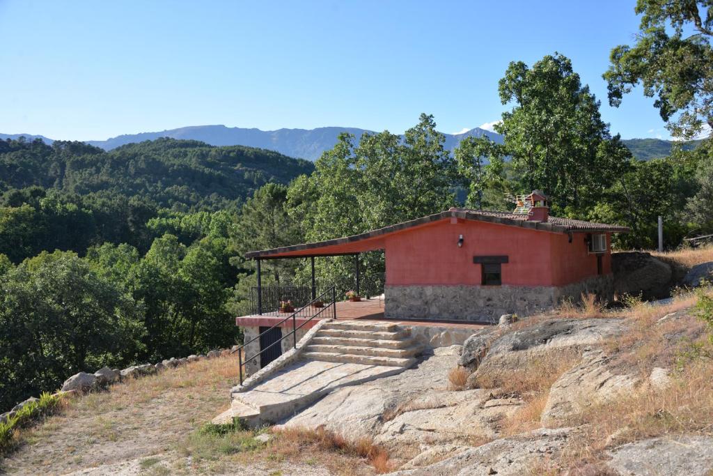 a small red building on a hill with trees at El Retiro de Ceubia by RetiroRural in Arenas de San Pedro