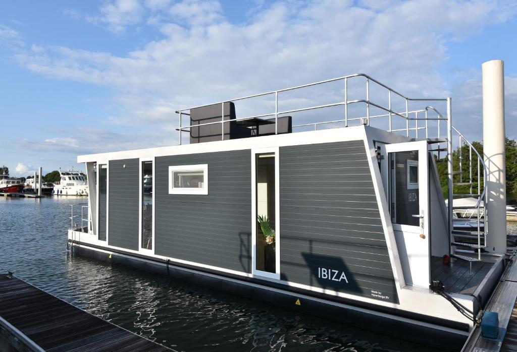 Tiny floating house Ibiza في ماستريخت: منزل على قارب في الماء