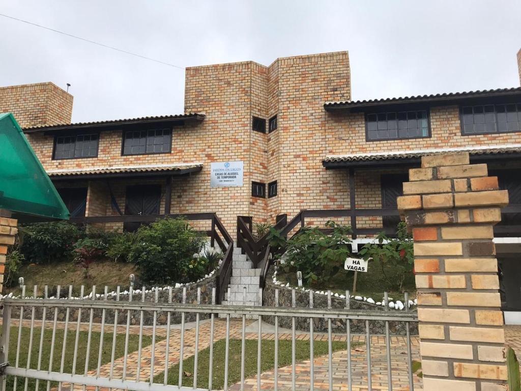 un edificio di mattoni con una recinzione di fronte di Jardim da Lagoa Casas de aluguel de temporada a Garopaba