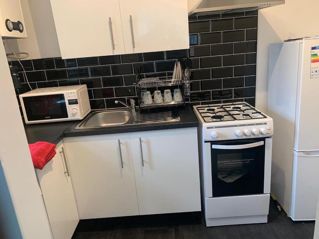 a small kitchen with a stove and a sink at Watford Town centre Apartment in Watford