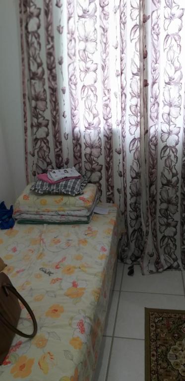 a bed sitting in front of a window with curtains at Condomínio Conquista Premium Aleixo in Manaus