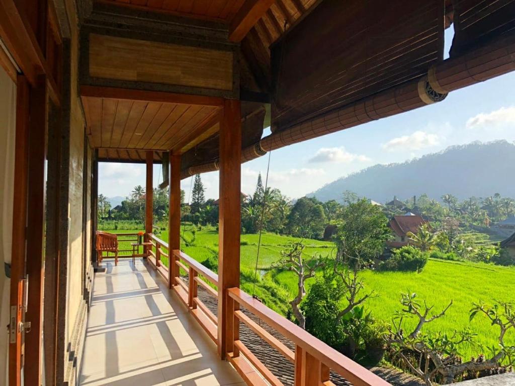 un balcón de una casa con vistas a un campo verde en Noka Homestay en Sidemen