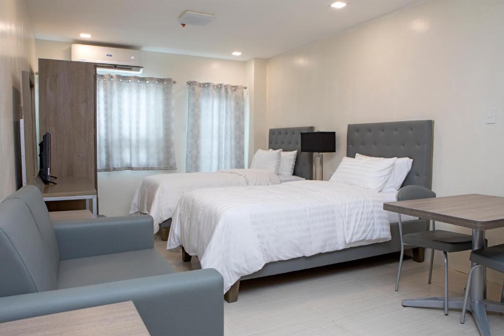 a hotel room with two beds and a table at Hotel Merlo in Manila