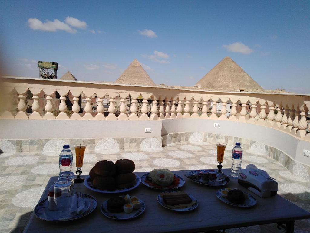 Queen Pyramids View Inn في القاهرة: طاولة عليها أطباق من المواد الغذائية والمشروبات