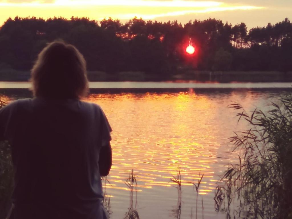 une personne debout devant un lac au coucher du soleil dans l'établissement Ferienwohnung Castelnau, à Trèves