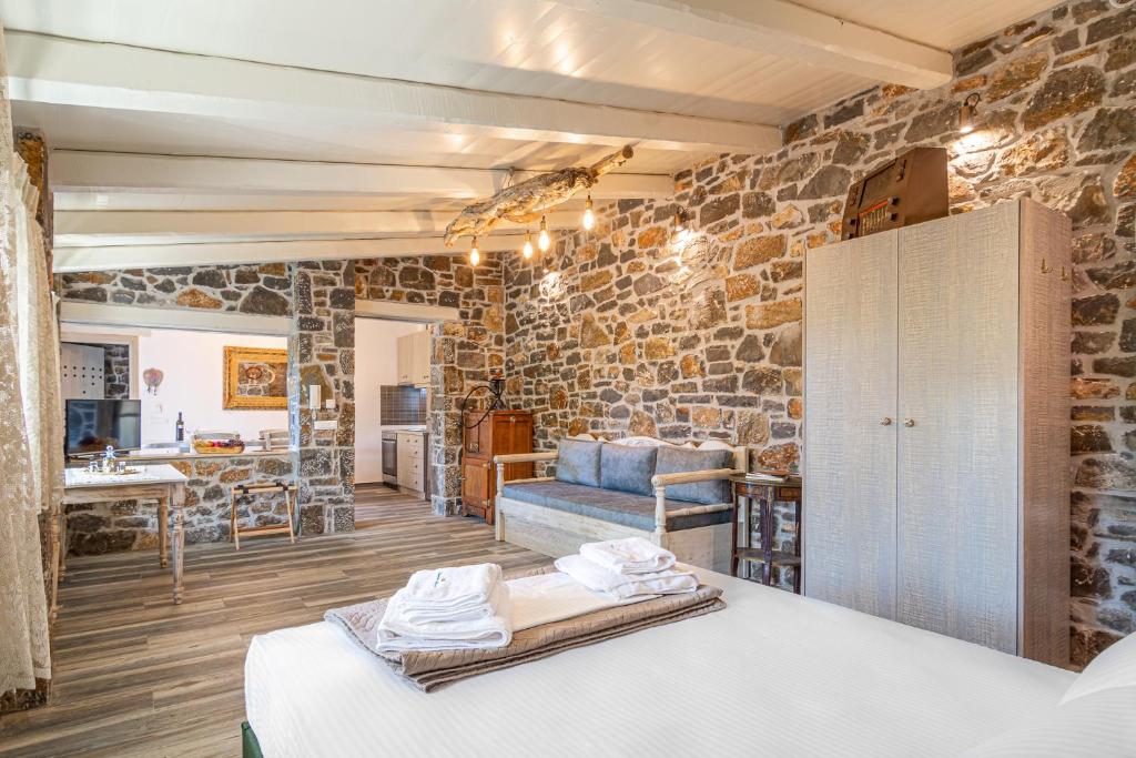 Zimmer mit einer Steinmauer, einem Bett und einem Sofa in der Unterkunft Perachori Boutique Studios in Anogia