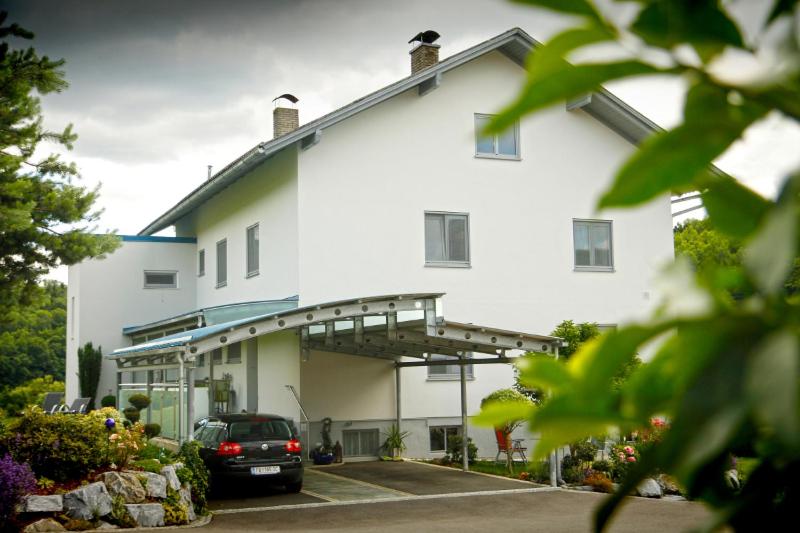 a white building with a car parked in a parking lot at Haus Steinfeld in Kirchberg an der Raab