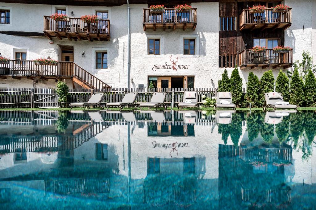 a hotel with a swimming pool in front of a building at Zum Alten Moar in Bressanone
