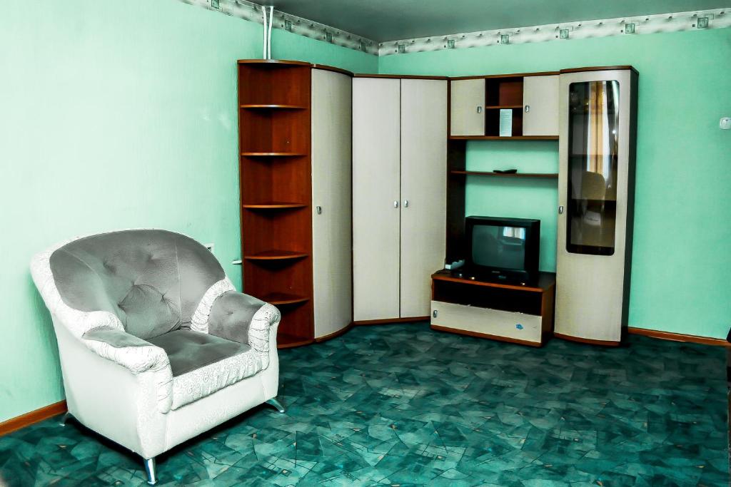 a living room with a chair and a television at Апартаменты Кирова, 83 in Rakitnyy