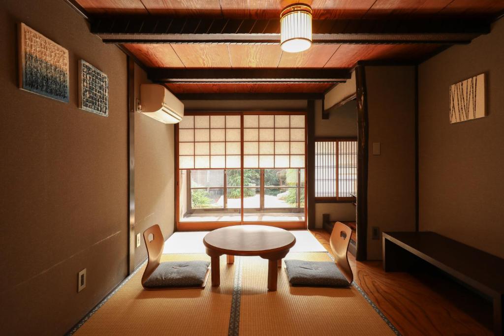 a room with a table and chairs and a window at Yurakuan - Awagami Residence Inn in Kyoto