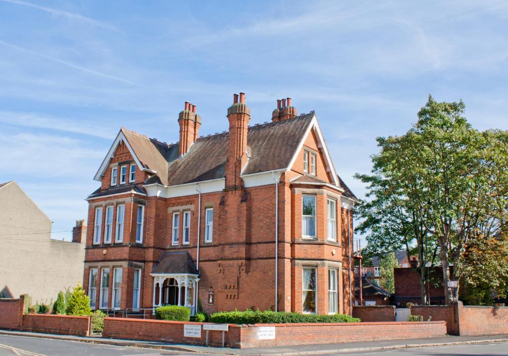 uma velha casa de tijolos vermelhos ao lado de uma rua em Holywell House em Loughborough