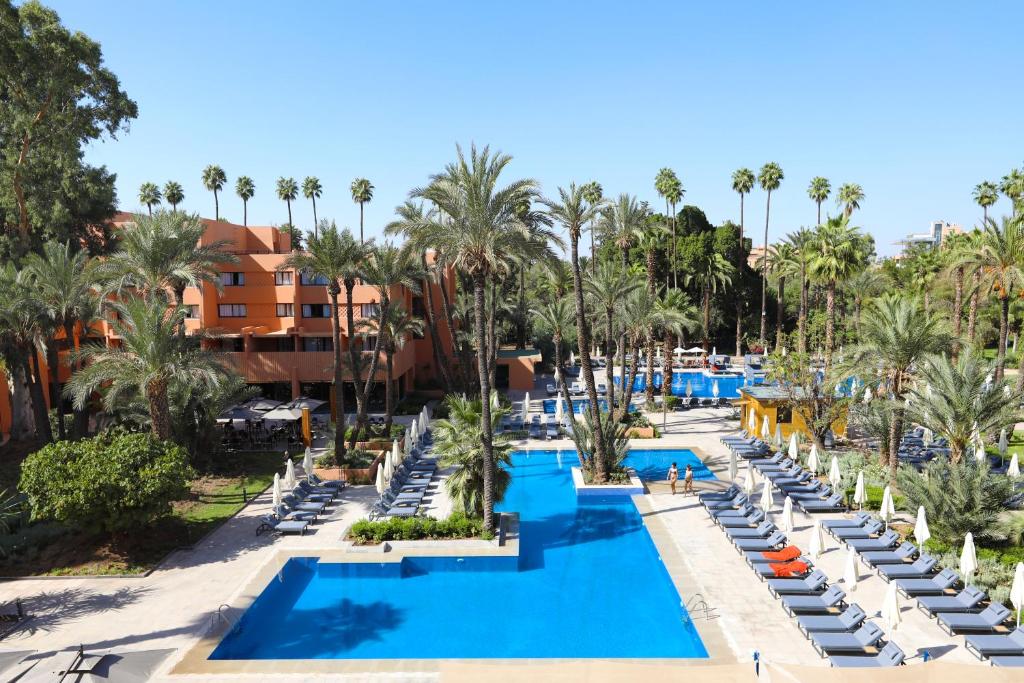 an aerial view of a resort pool with lounge chairs and palm trees at Kenzi Rose Garden in Marrakech