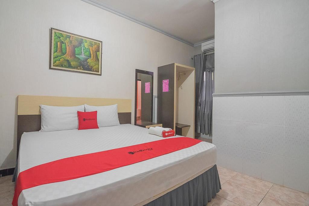 a bedroom with a large bed with a red blanket at RedDoorz Syariah near Taman Rozeline Penajam in Balikpapan