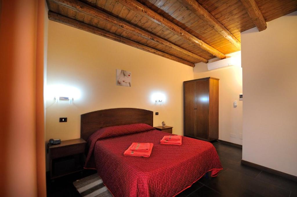 1 dormitorio con 1 cama roja y 2 toallas rojas. en Hotel Piccolo, en Termini Imerese