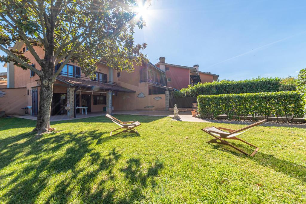 two benches sitting in the grass in front of a house at La Luna sul lago in Trevignano Romano