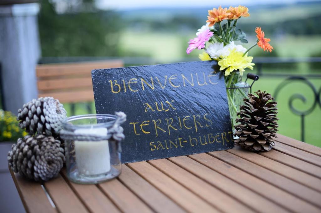 een kaars en een boek op een tafel met bloemen bij Les Terriers Saint-Hubert in Hatrival