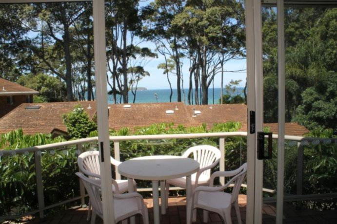 a table and chairs on a porch with a view of the ocean at Coastal Retreat Unit 5 in Sunshine Bay