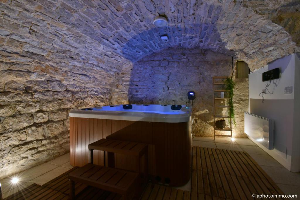 uma casa de banho com uma banheira numa parede de pedra em Les Bouc'tins em Molain