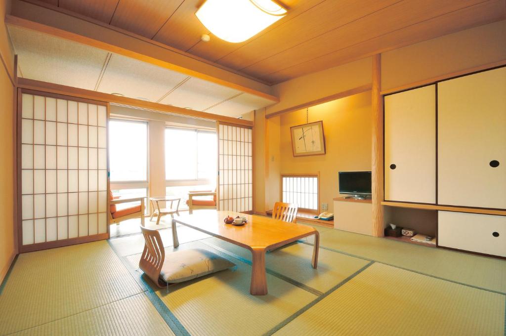 um quarto com uma mesa e cadeiras num quarto em Miyahama Grand Hotel em Hatsukaichi