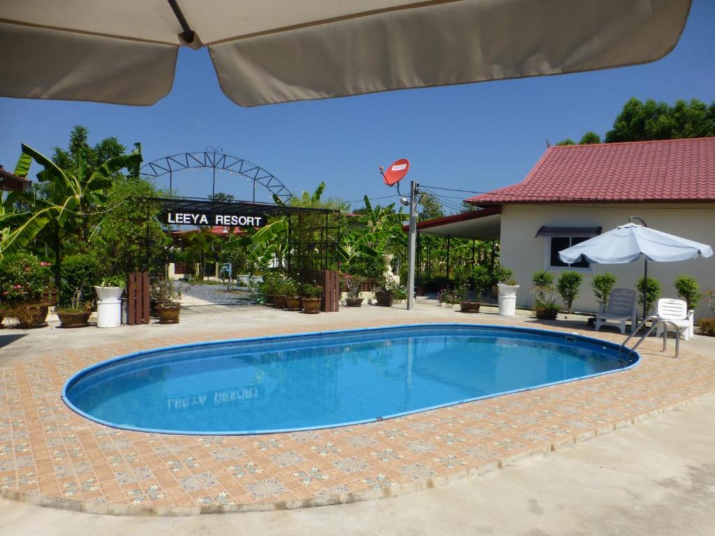 a swimming pool at a resort with an umbrella at Private 2 bedroom villa with Swimming pool Tropical gardens Fast Wifi smart Tv in Ban Sang Luang