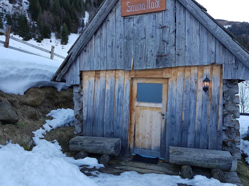 a wooden cabin with a door in the snow at Der Perweinhof in Donnersbachwald