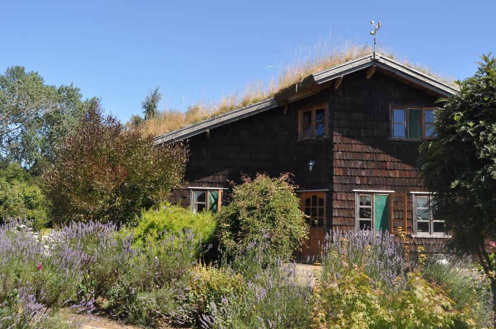 a wooden house with a garden in front of it at Zapato Amarillo Bed & Breakfast in Puerto Octay