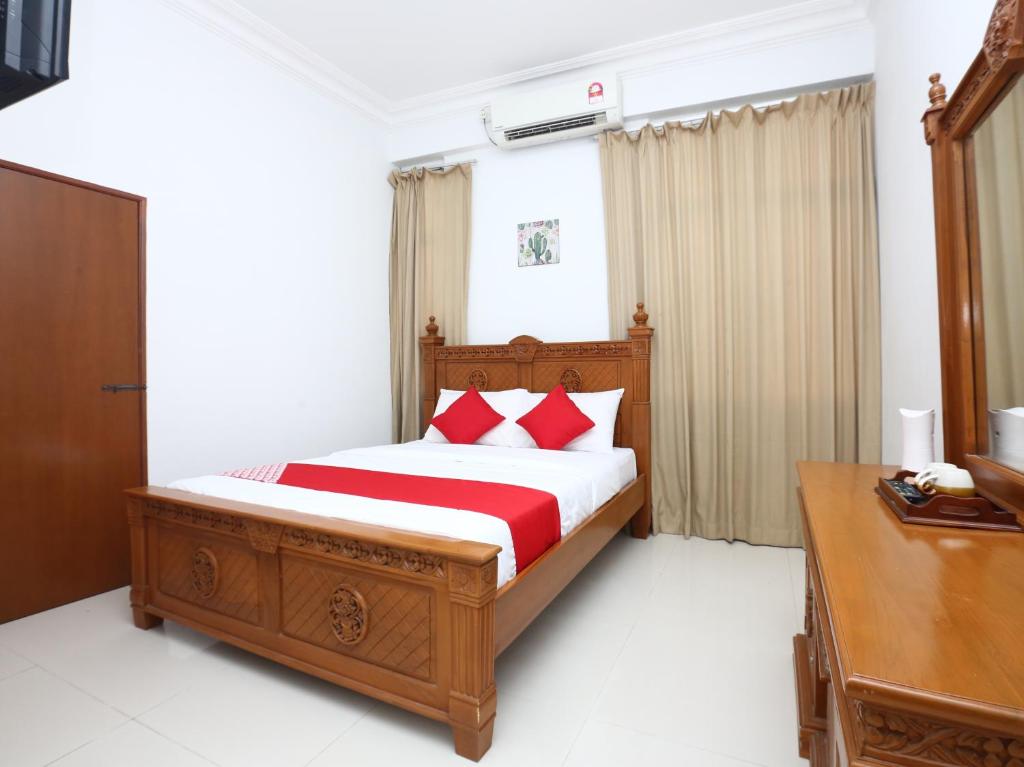 a bedroom with a bed with red pillows at Super OYO 89435 Nusantara Group Hotel in Jertih
