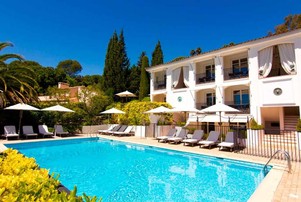 a swimming pool in front of a building with chairs and umbrellas at Hotel les Vergers de Saint Paul in Saint Paul de Vence