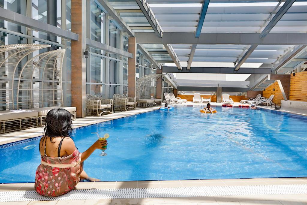 a woman sitting in front of a swimming pool at VIP Hotel Doha Qatar in Doha