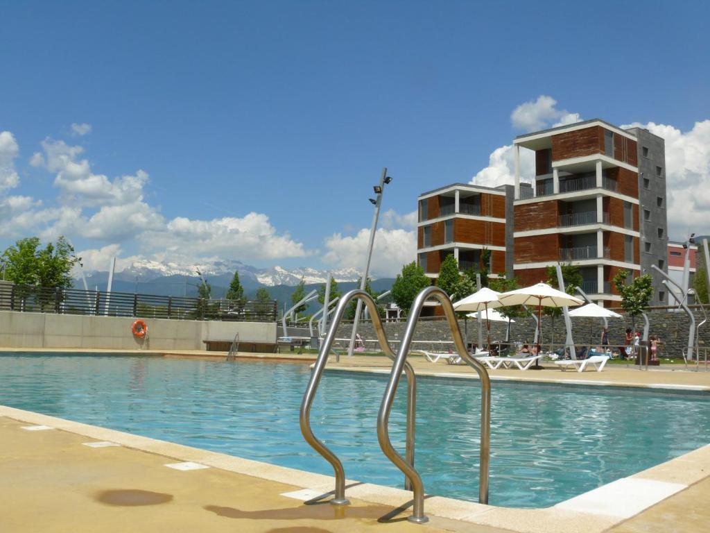 una piscina con sillas y un edificio en APARTMENTSUITESPAIN FORMIGAL ORDESa, en Sabiñánigo