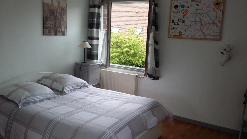1 dormitorio con cama y ventana en 2 Chambres de 16m2 à 10kms de Lille, en Beaucamps-Ligny