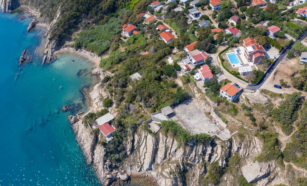 eine Luftansicht einer Gruppe von Häusern auf einem Hügel neben dem Wasser in der Unterkunft Luxury Seafront Villa Exclusive Pag with private pool by the beach on Pag island in Pag