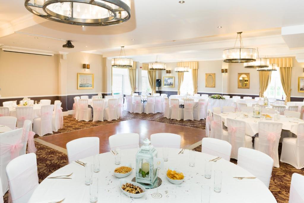 a banquet hall with white tables and white chairs at The Marine in Whitstable