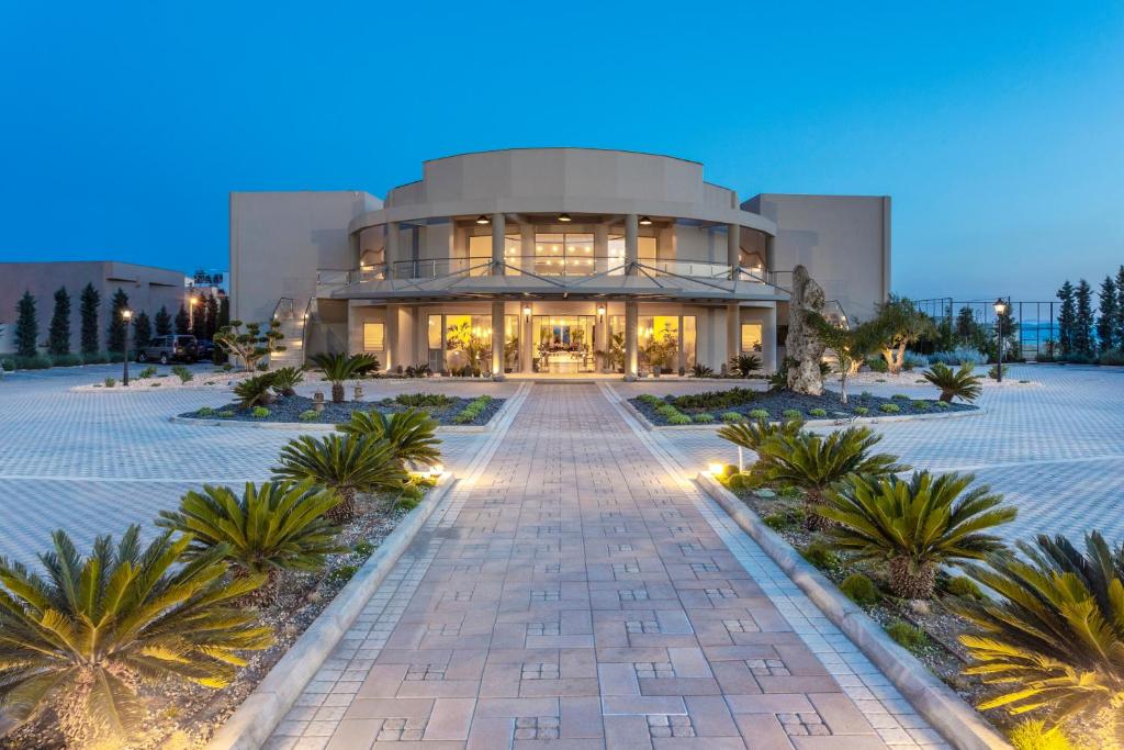 un grand bâtiment avec des palmiers devant lui dans l'établissement Elysian Luxury Hotel and Spa, à Kalamata