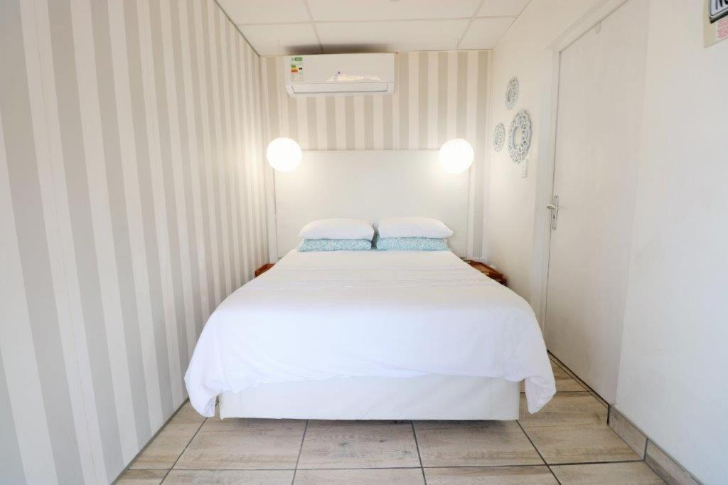 1 dormitorio con cama blanca y almohadas azules en 17 Umdloti Resort, en Umdloti