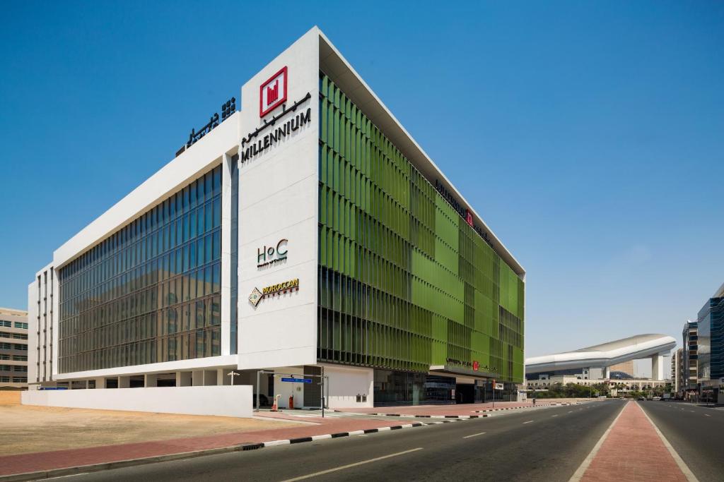 a large office building with a green and white facade at Millennium Al Barsha in Dubai