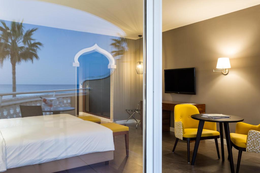 a hotel room with a bed and a table and chairs at AP Oriental Beach - Adults Friendly in Portimão