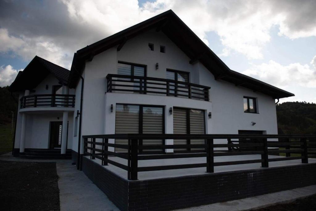 a white house with a black roof at Casa Florus in Sighetu Marmaţiei