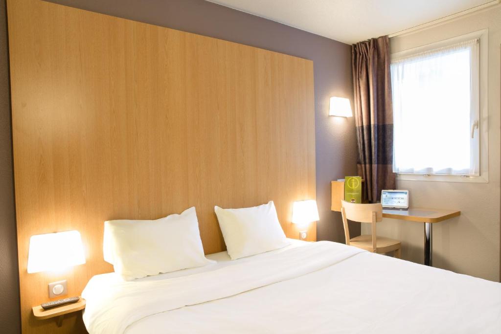 a hotel room with a bed with two pillows and a window at B&B HOTEL Montpellier 2 in Saint-Jean-de-Védas