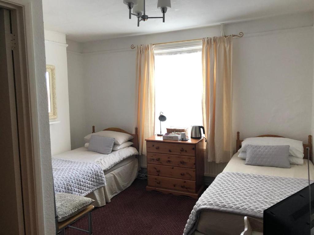 um quarto com 2 camas e uma janela em The Prince of Wales em Reigate