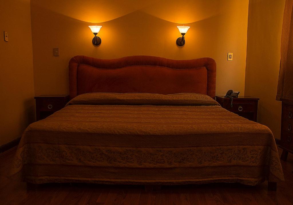 a bedroom with a bed with two lights on the wall at Hotel Roma in Durango