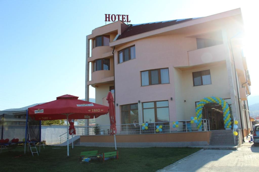 ein Hotel mit einem Regenschirm neben einem Gebäude in der Unterkunft Семеен Хотел Дани in Assenowgrad