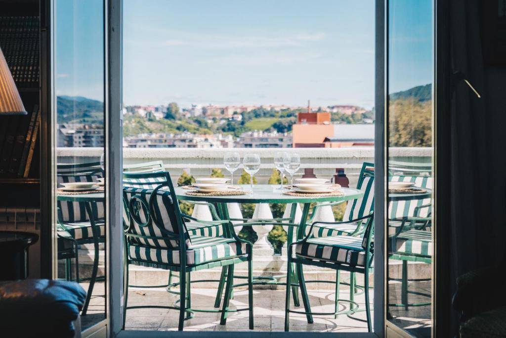 a table with chairs and wine glasses on a balcony at Mirador by People Rentals in San Sebastián