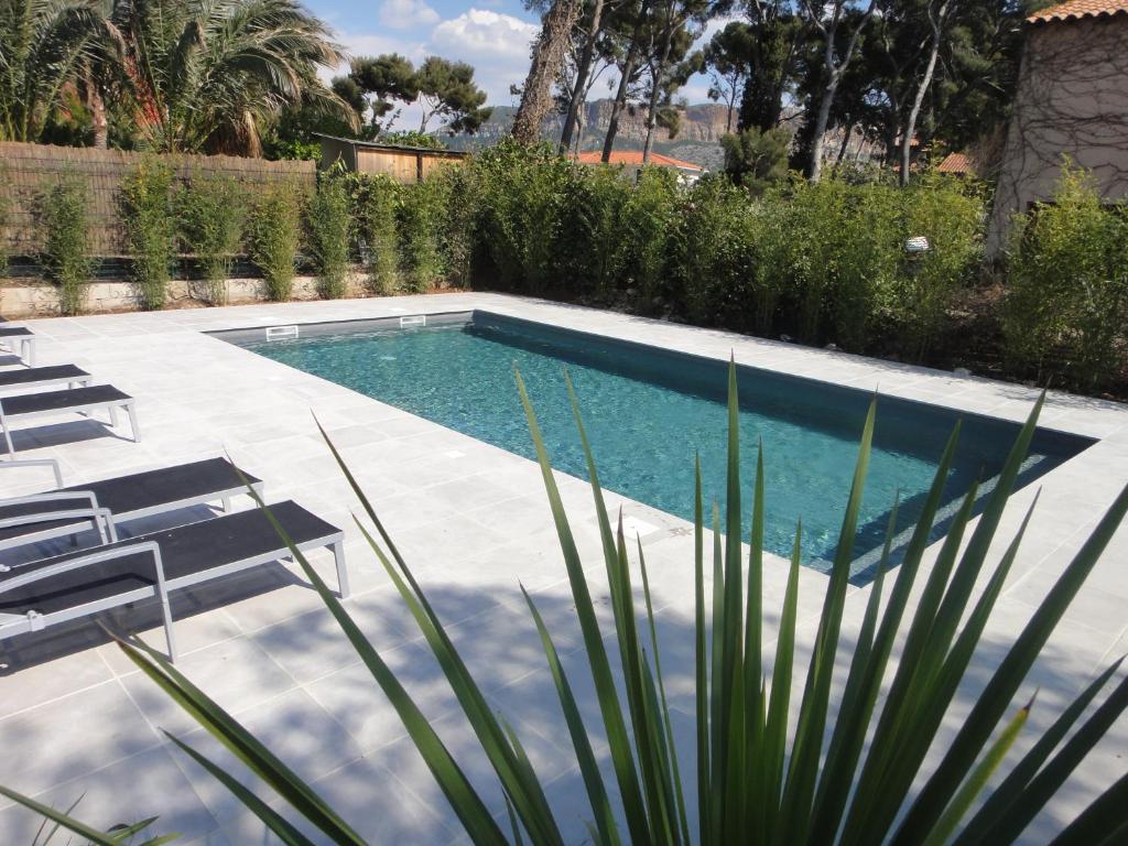 uma piscina num quintal com cadeiras e árvores em Home Cassis - Maison Les Calanques - Piscine chauffée em Cassis