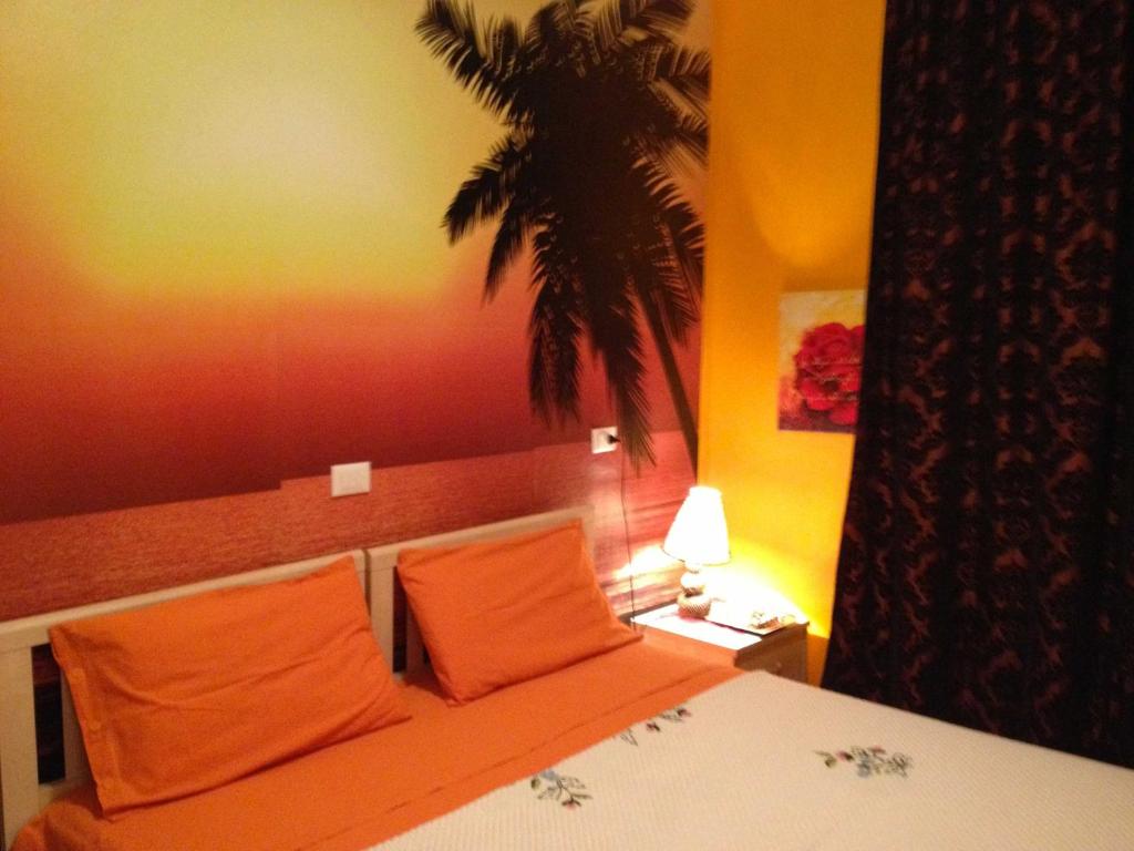 ビビオーネにあるCasa Augusta Apartmentのベッドルーム1室(オレンジの枕とヤシの木のベッド1台付)