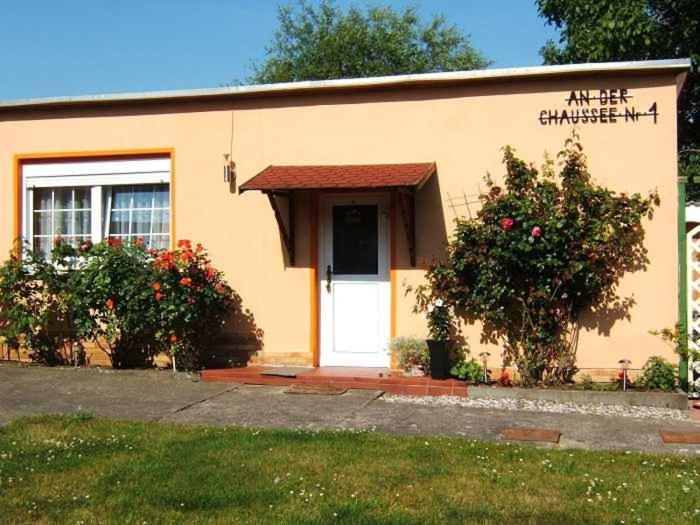 un pequeño edificio amarillo con una puerta blanca y flores en Ferienwohnung Sehlen auf Ruegen, en Sehlen