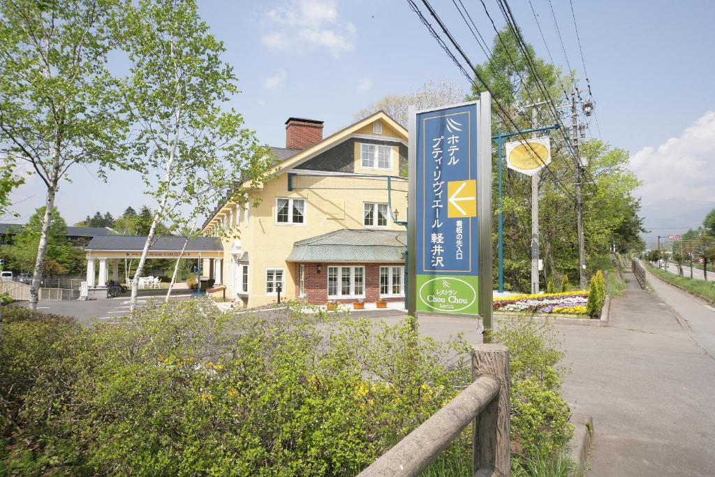 a sign in front of a house on a street at Hotel Petit Riviere Karuizawa in Karuizawa